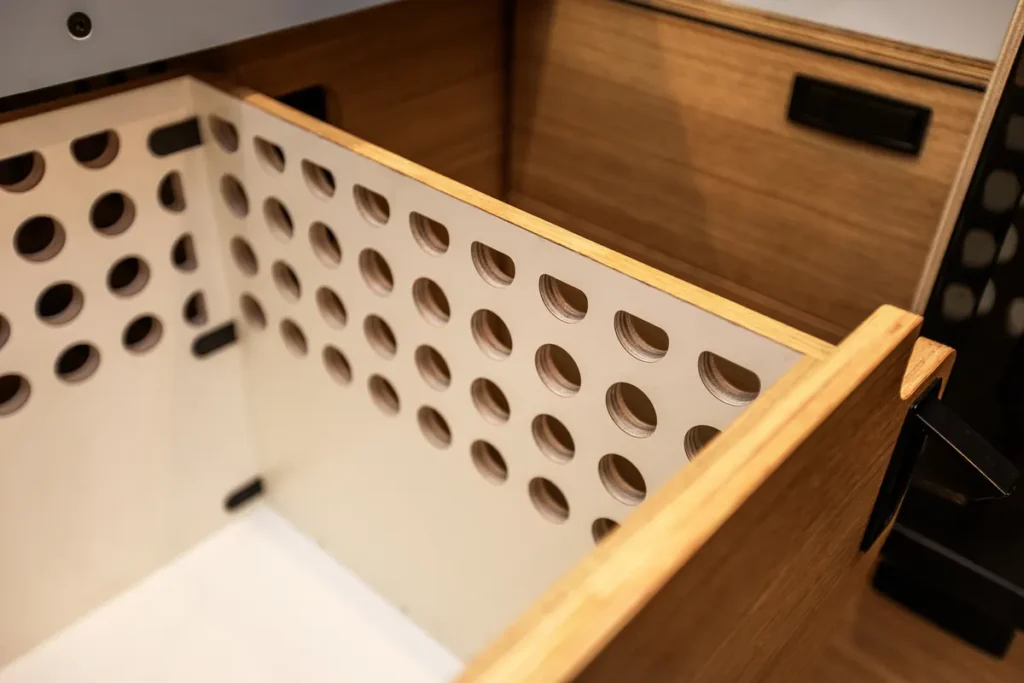 Geöffnete Schublade mit Lochmuster und sauber verarbeiteten Holzkanten