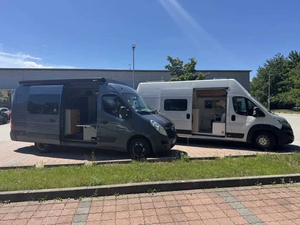 Zwei ausgebaute Kastenwagen nebeneinander mit geöffneten Schiebetüren